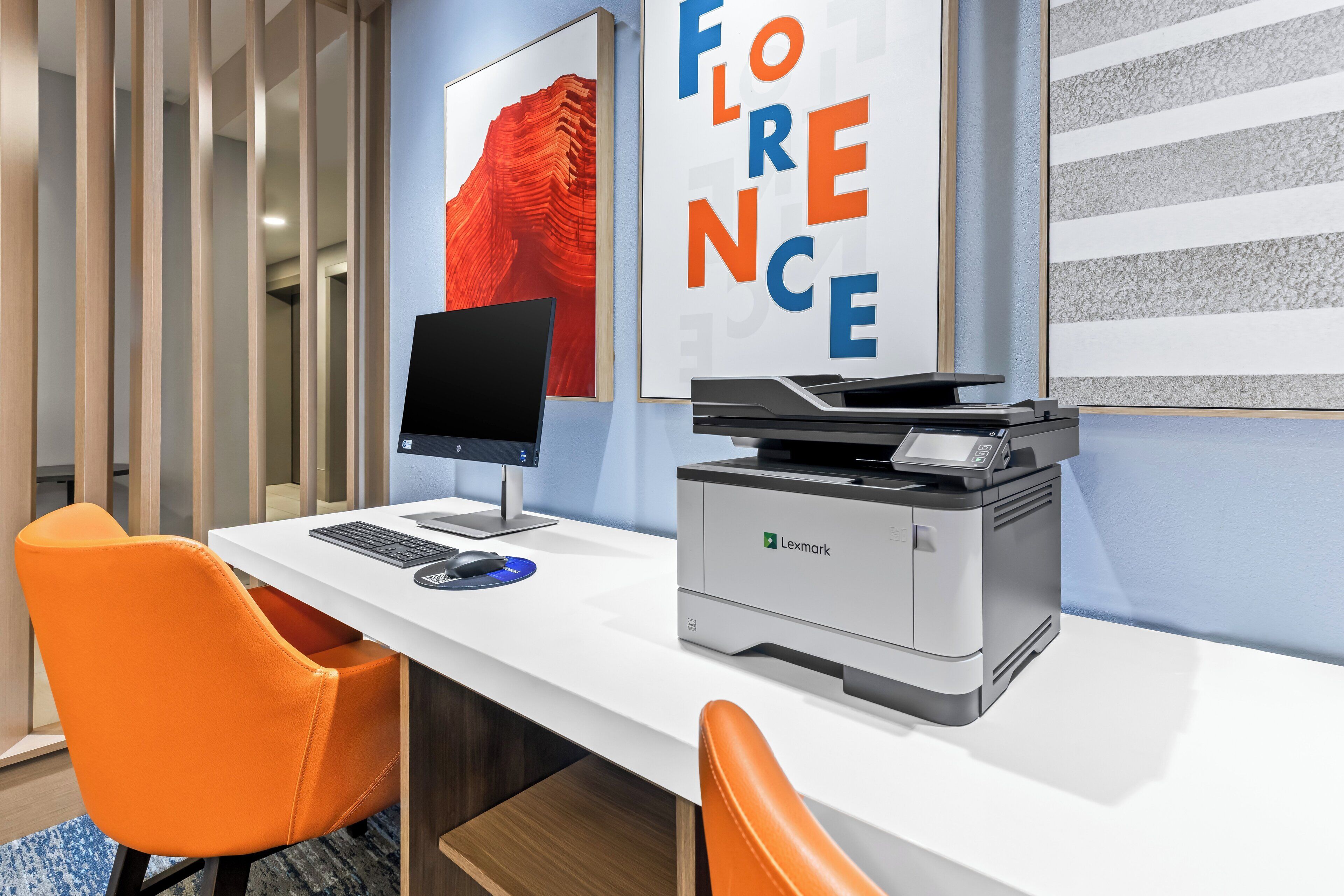 A modern office space with a white desk, an orange chair, a desktop computer, and a Lexmark printer.