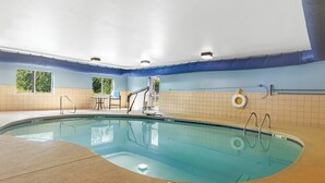 Ein Hallenbad mit klarem Wasser, gefliesten Wänden und einem Rettungsschwimmerstuhl.