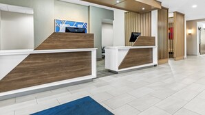 Ein Empfangsbereich mit zwei Holztresen, einem blauen Teppich und einem modernen Interieur.