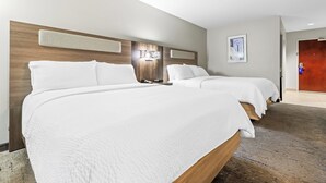 Ein Hotelzimmer mit zwei Betten, einem Holzkopfteil, einer Wandleuchte und einem gerahmten Bild.