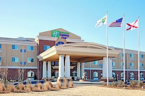 A Holiday Inn Express & Suites hotel with a prominent entrance, multiple flags, and a landscaped area with a fountain. - Holiday Inn Express Hotel & Suites FLORENCE NORTHEAST by IHG (Florence)