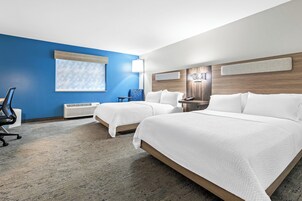 Habitación de hotel con dos camas, una pared azul decorativa, un ventanal grande y un diseño moderno.