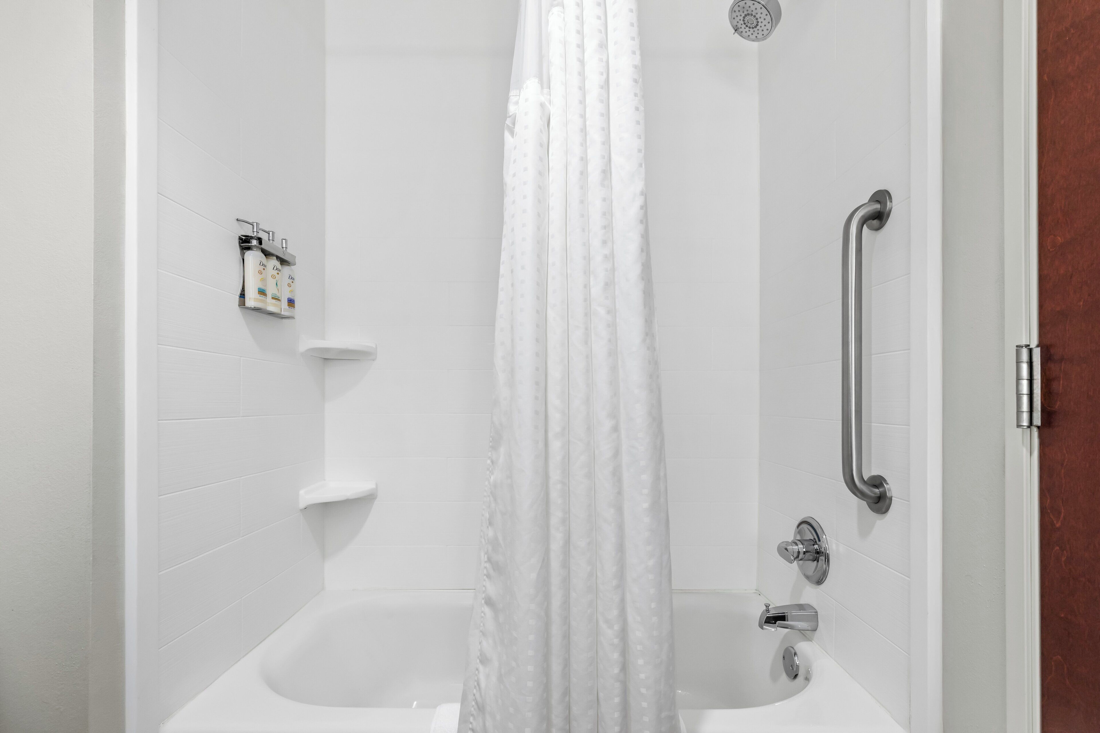A modern bathroom with a shower, grab bars, and a toilet.