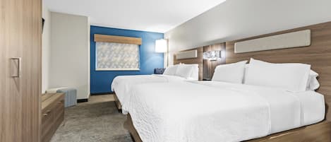 Een moderne hotelkamer met een groot bed, een houten garderobe, een blauwe accentmuur en een raam met zonwering.