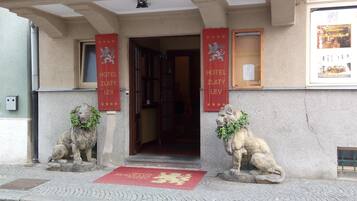 A hotel entrance with two lion statues, red banners, and a red doormat.