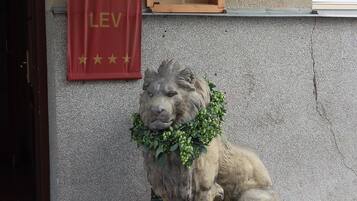 Une statue de lion surmontée d’une bannière rouge et accompagnée d’une pancarte en bois avec du texte.
