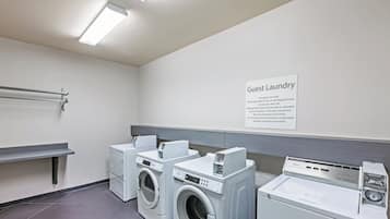 A guest laundry area with a sign, two front-loading washers, and a dryer.