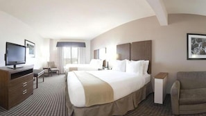 Relax in a spacious room with a large bed, flat-screen TV, and comfortable armchair.