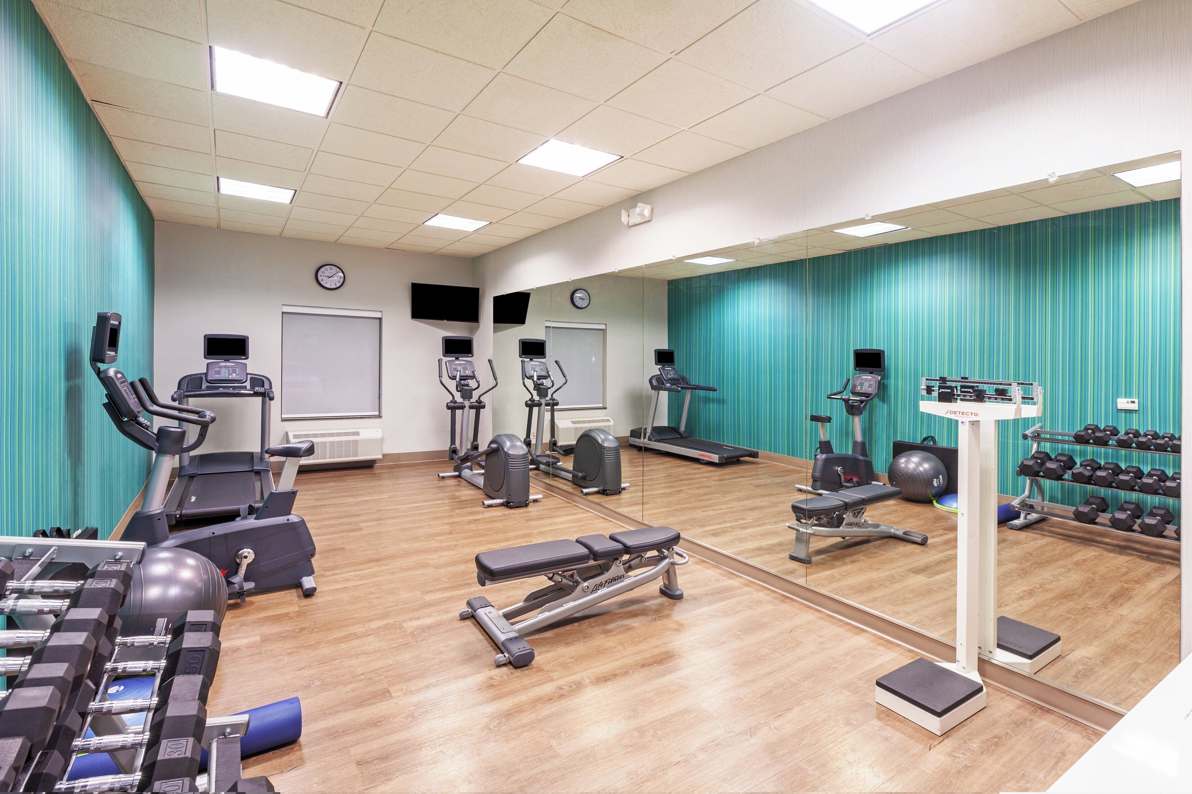 A gym with various exercise equipment, including treadmills, stationary bikes, and dumbbells.