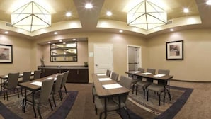 A conference room with a long table, multiple chairs, a kitchenette, and a door. - Holiday Inn Express Hotel & Suites PORT ARTHUR by IHG (Port Arthur)