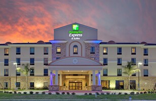 Un hotel Holiday Inn Express & Suites con fachada de piedra y una entrada amplia.