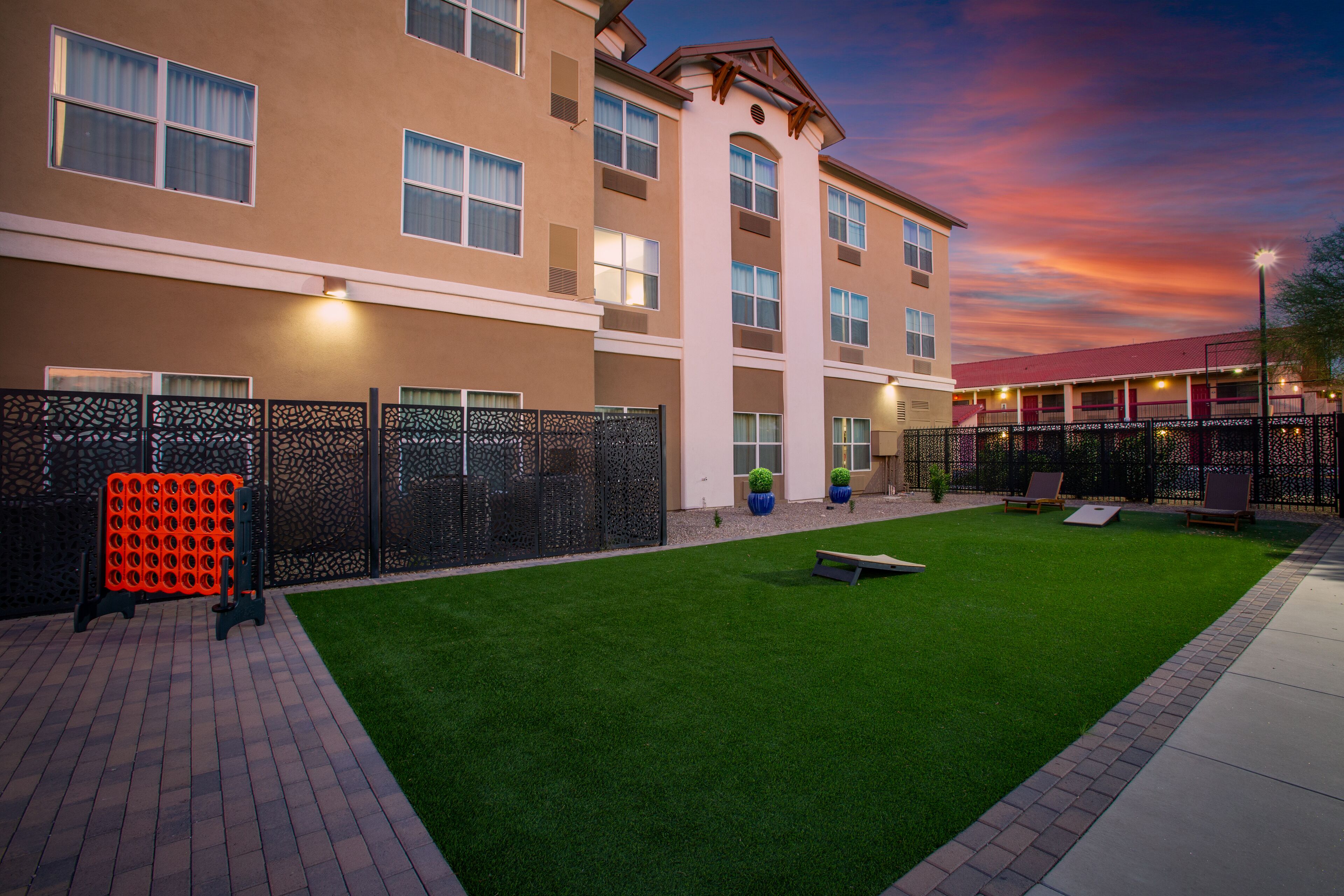 A hotel courtyard with artificial grass, a pool table, and a fenced area.
