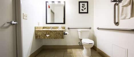 Un baño pequeño con inodoro, lavamanos de encimera de granito, espejo y barra para toallas.