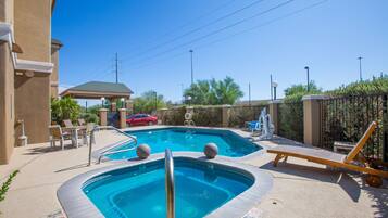 A swimming pool with lounge chairs and a covered seating area.