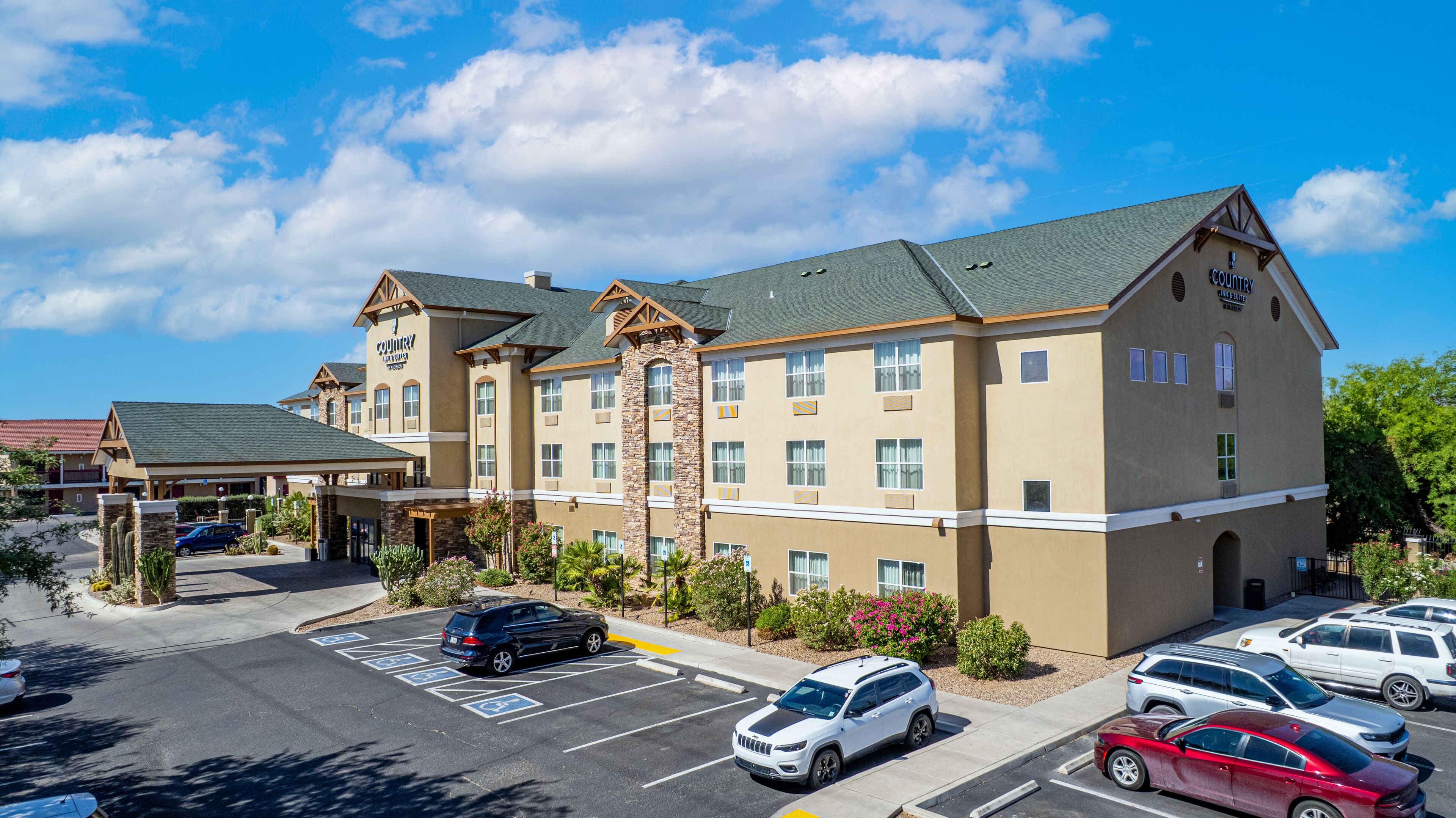 A multi-story hotel with a central courtyard, parking lot, and a covered entrance.