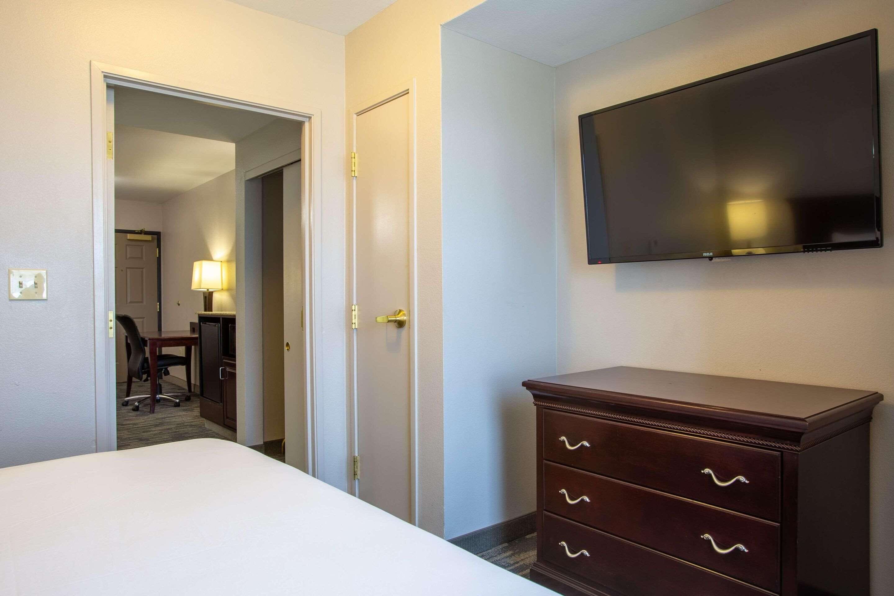 Une chambre d’hôtel comprenant un lit, une commode, un téléviseur et un bureau avec une chaise.