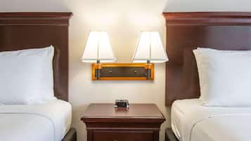 A hotel room with two beds, a nightstand with a clock, and wall-mounted lamps.
