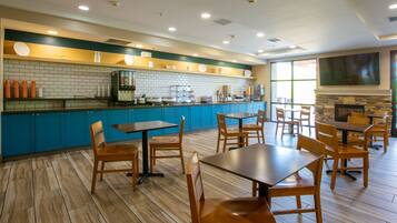 A restaurant with blue cabinets, wooden tables, and chairs.