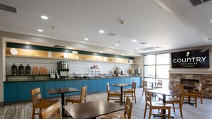 A restaurant with a counter, tables, and chairs. - Country Inn & Suites by Radisson, Tucson City Center, AZ (Tucson)