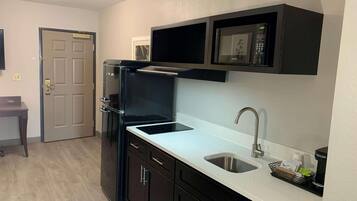 A compact kitchen with a built-in microwave, a stainless steel sink, and dark cabinetry.