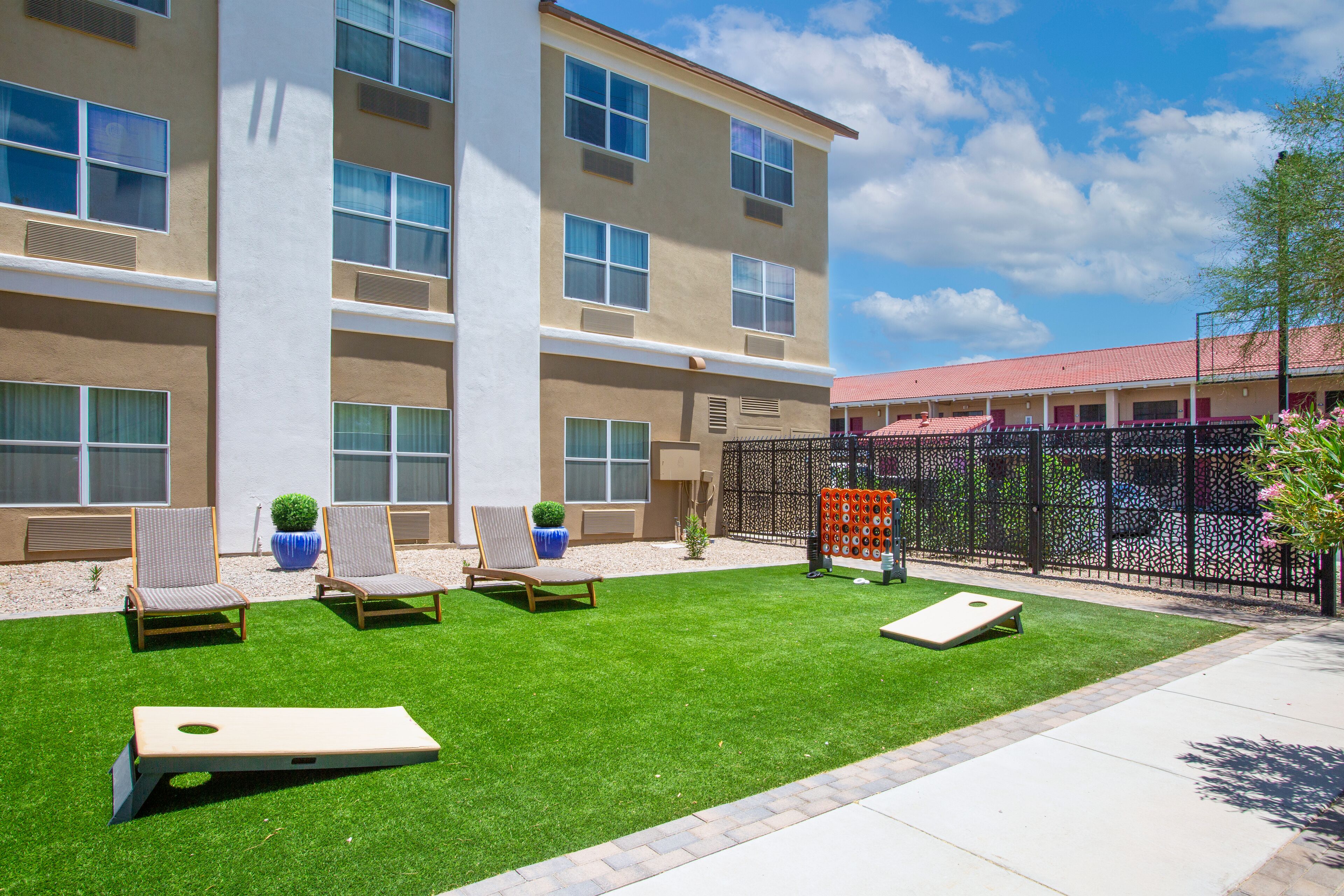 A courtyard with a lawn, outdoor seating, and a building with multiple windows and balconies.