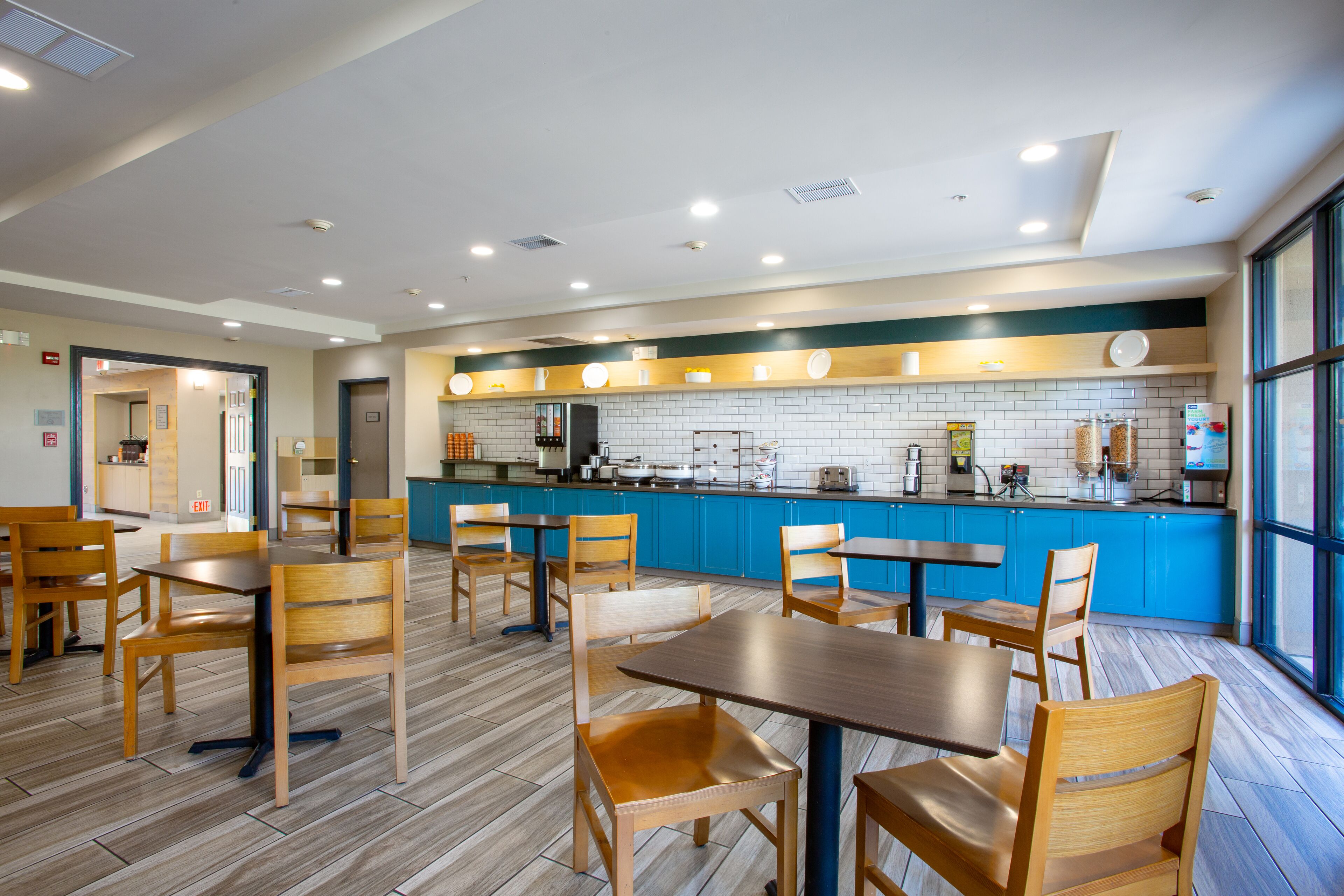 Un restaurante moderno con mesas y sillas de madera, una barra azul y un salpicadero de azulejos.