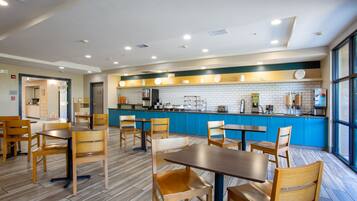 Un restaurante moderno con mesas y sillas de madera, una barra azul y un salpicadero de azulejos.