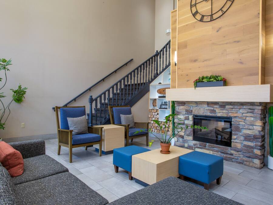 Una sala de estar moderna con chimenea de piedra, muebles tapizados en azul y una escalera.