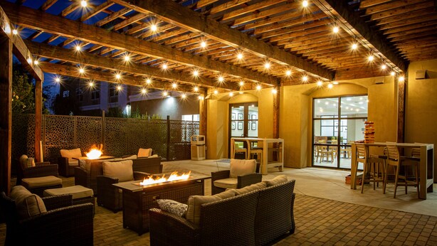 An outdoor patio area with wicker furniture, a fire pit, and string lights. - Country Inn & Suites by Radisson, Tucson City Center, AZ (Tucson)
