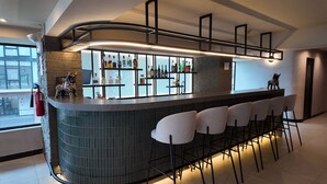Un espace bar moderne doté d’un comptoir incurvé, de tabourets de bar et d’une variété de bouteilles d’alcool.