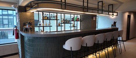 A modern bar area with a curved counter, bar stools, and a variety of liquor bottles.