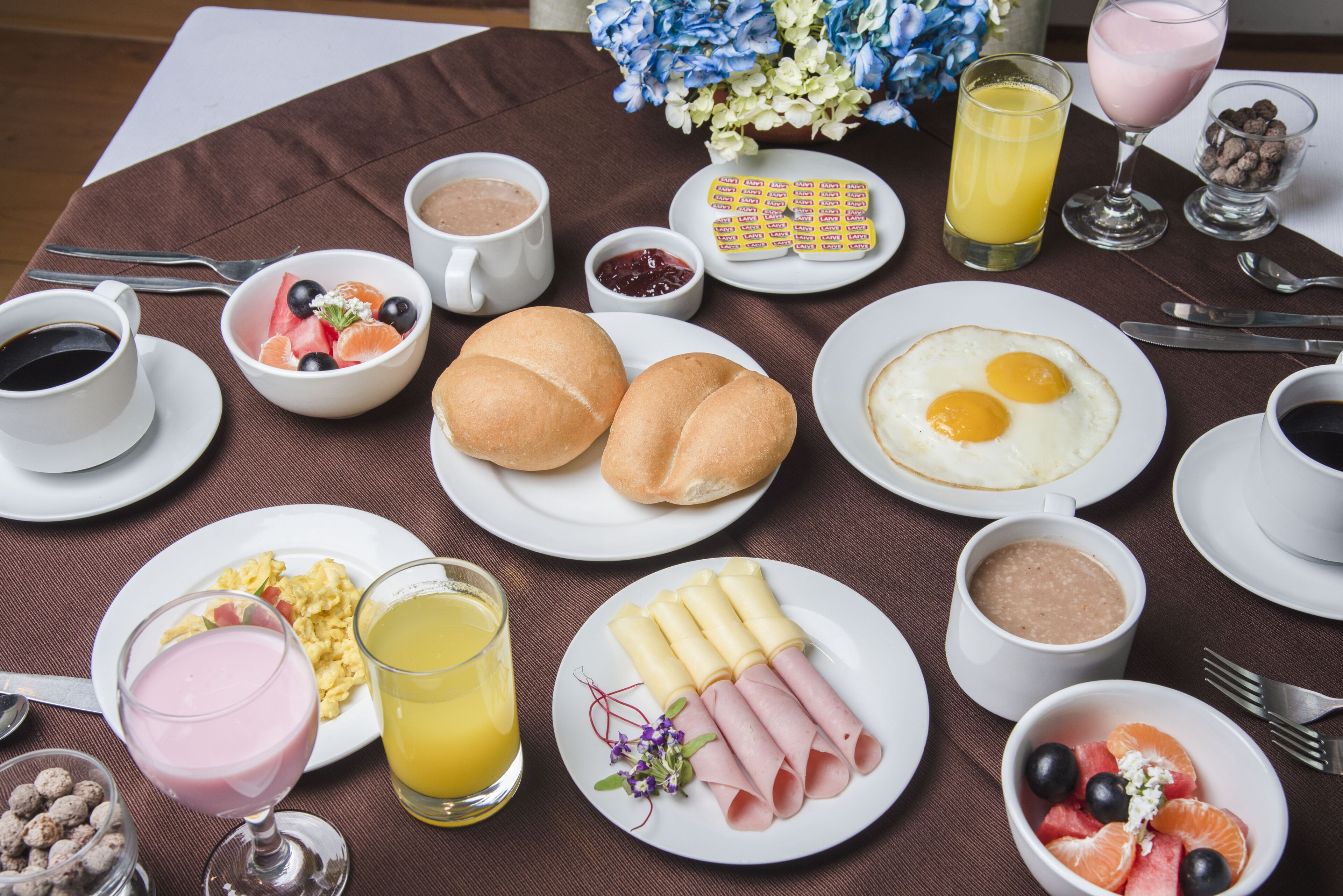 A breakfast table with various food items and drinks.
