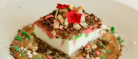 A dessert with a layered structure, topped with colorful sprinkles and a flower, served on a white plate.