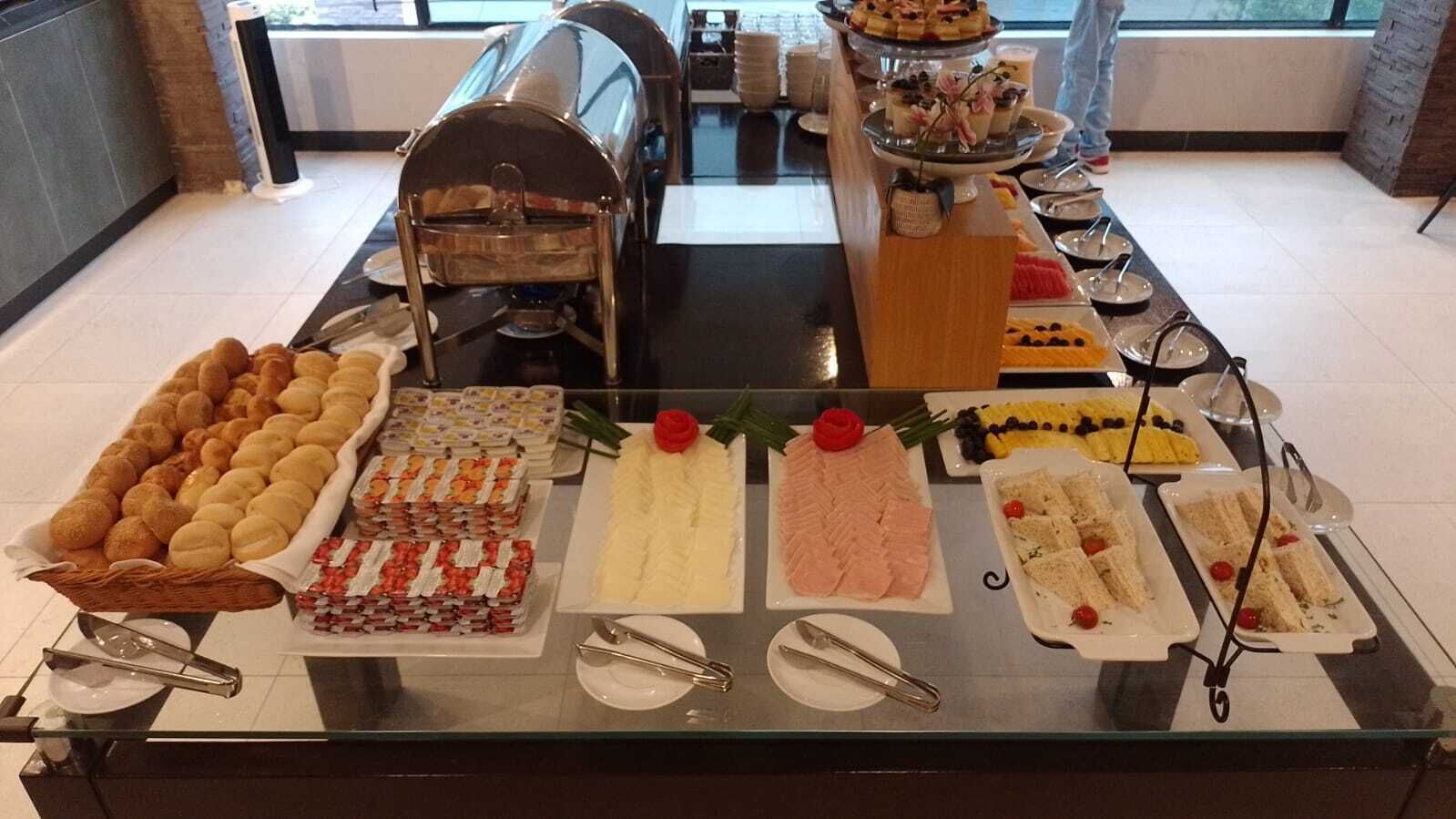 Un bufé con diversas opciones de comida, incluyendo pan, pasteles y sándwiches.