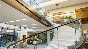 A modern interior with a curved glass staircase, a high ceiling with skylights, and a view of the outside. - Capital Plaza Hotel (Bucharest)