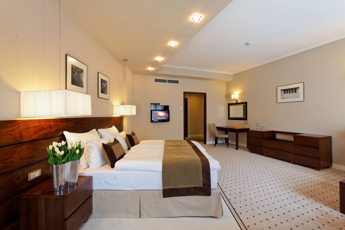 Ein Hotelzimmer mit Bett, Nachttischen, Schreibtisch, Stuhl und Fernseher.