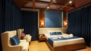 Ein Hotelzimmer mit einem großen Bett, einer Couch, einem Nachttisch und einer Holzbalkendecke.
