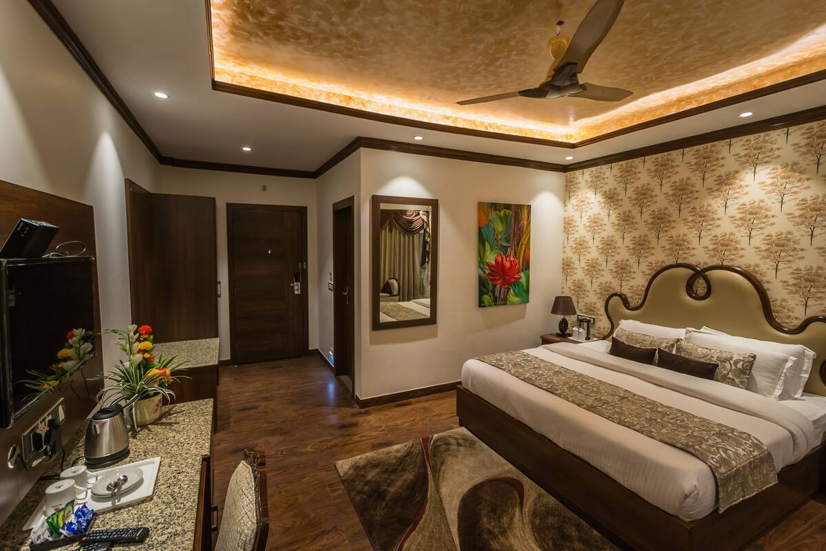A modern hotel room with a large bed, a ceiling fan, and a decorative mirror.