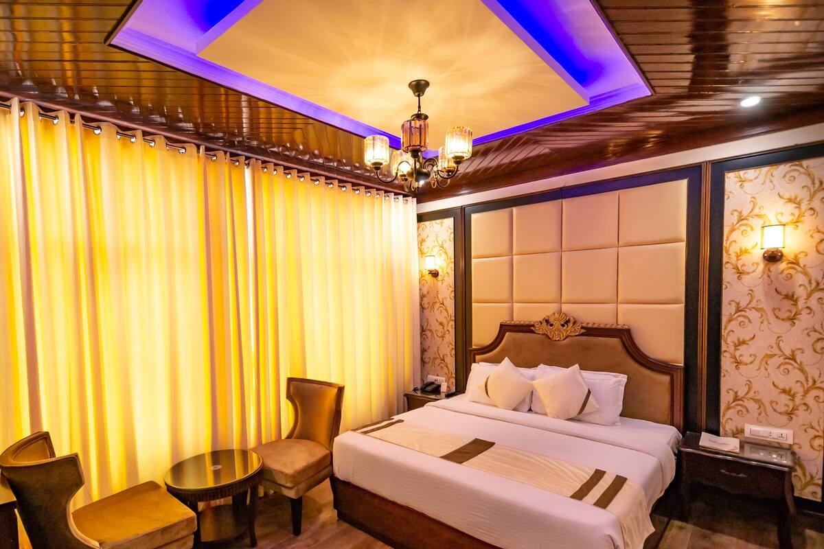 A hotel room with a large bed, a chair, a small table, and a nightstand.