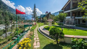 Ein Hotel mit Gartenweg, Sitzgelegenheiten im Freien und Bergblick.