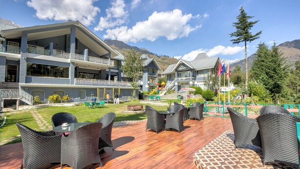 Ein Hotel mit einer Holzdiele, Korbmöbeln und Bergblick.