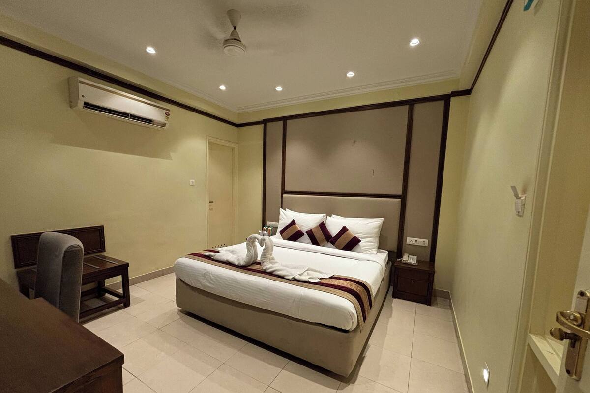 Habitación de hotel con una cama grande, un escritorio, una silla, un equipo de aire acondicionado y una puerta.