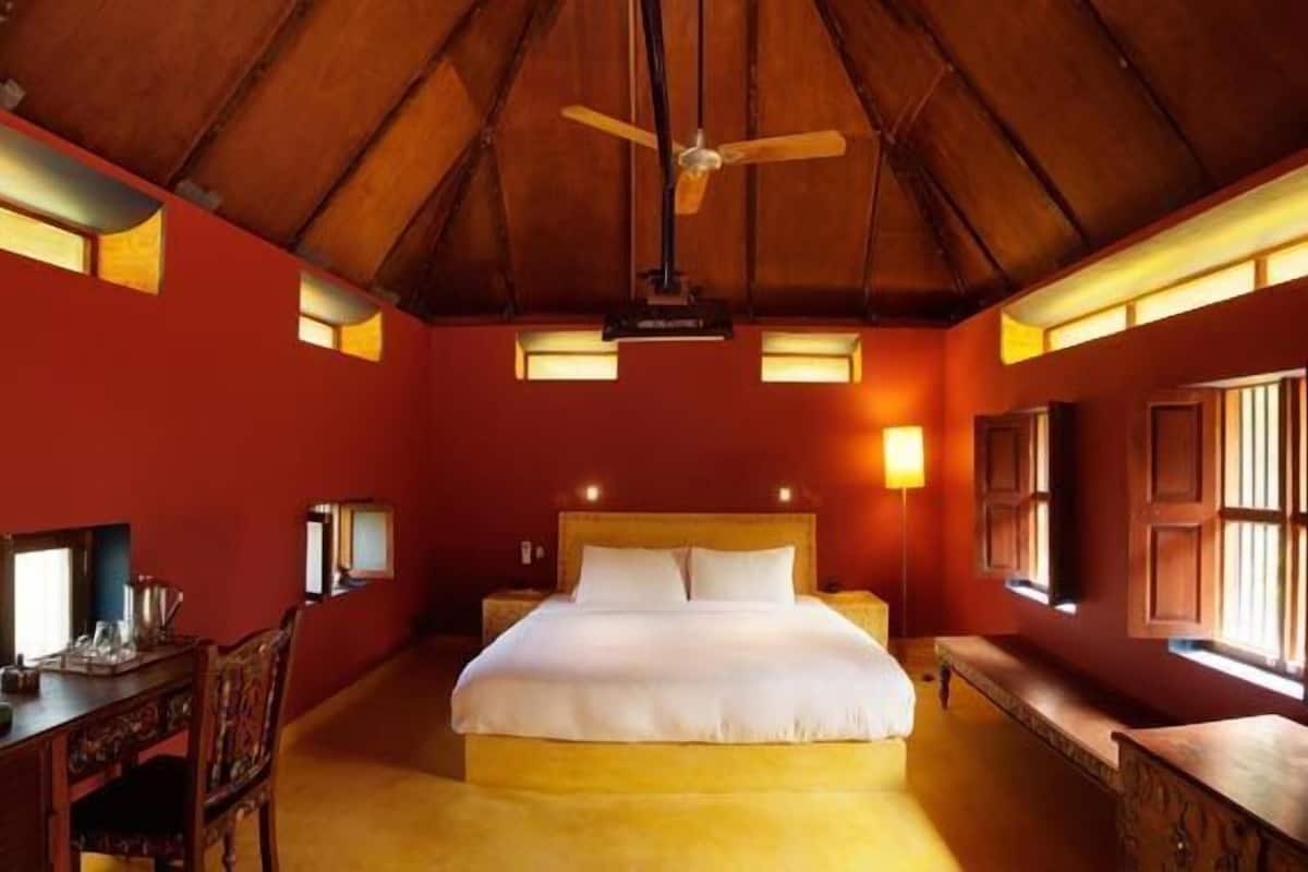 A bedroom with a wooden ceiling, a bed, a desk, and a chair.