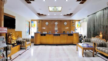 A reception area with a reception desk, a cash counter, and a reception sign. There are two sofas and a small table in the foreground.
