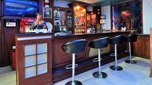 Eine Bar mit Theke, Hockstühlen und einem Fernsehbildschirm.
