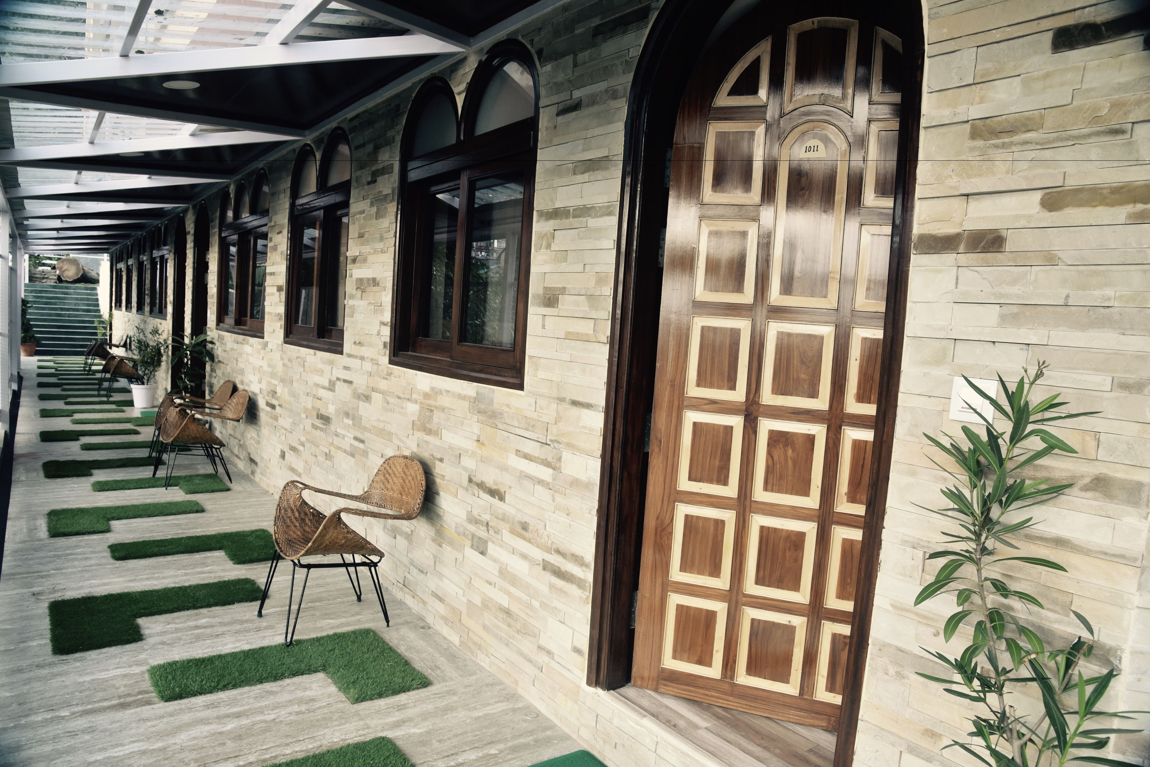 A corridor with a wooden door, stone walls, and green artificial grass.