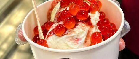 A cup of ice cream with red fruit toppings and a small umbrella, labeled 'Beyond Gelato.'