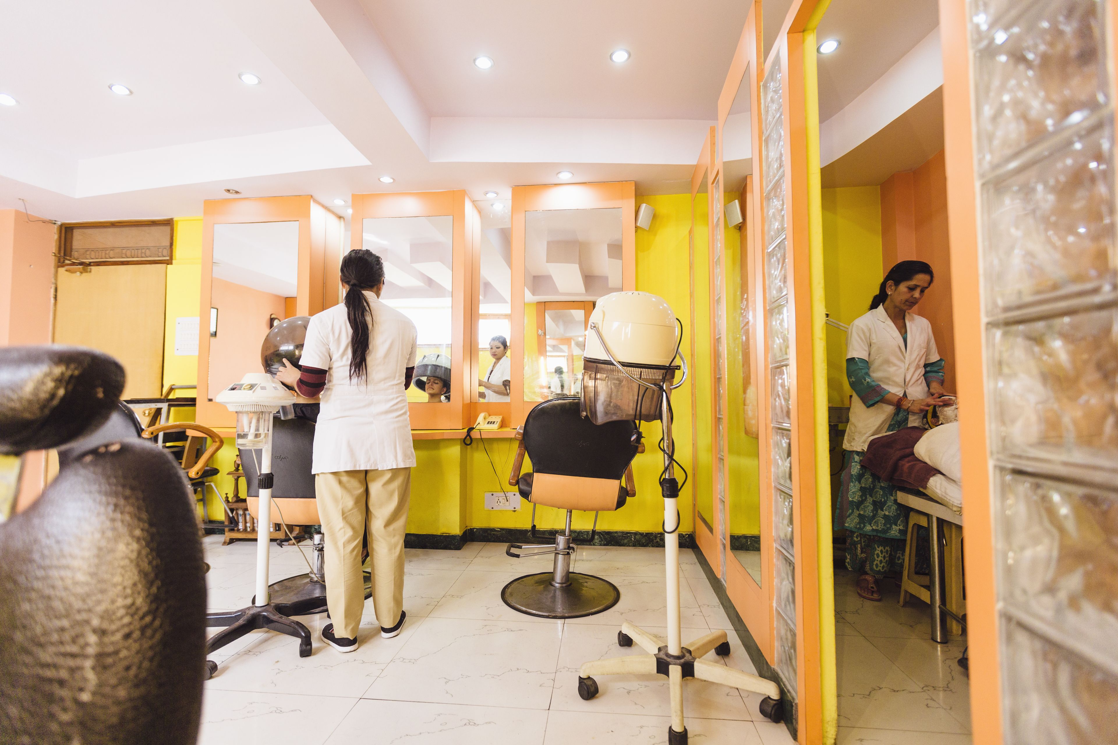 L'intérieur d'un salon de coiffure, avec un miroir, un sèche-cheveux et un fauteuil.