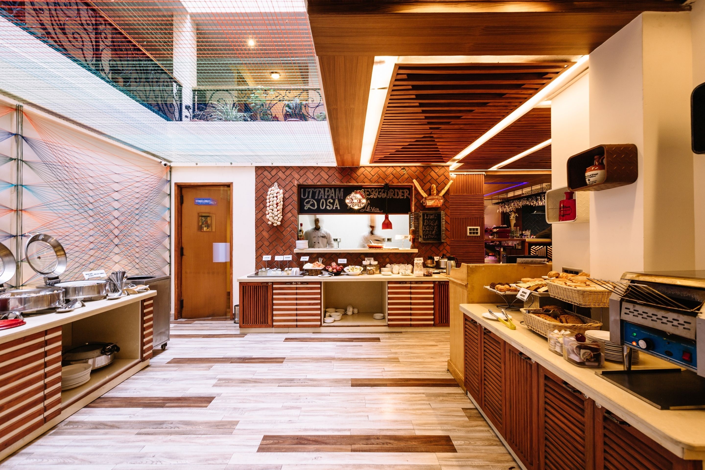 A modern kitchen area with a buffet setup, including a coffee machine and various food items.