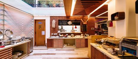 A modern kitchen area with a buffet setup, including a coffee machine and various food items.